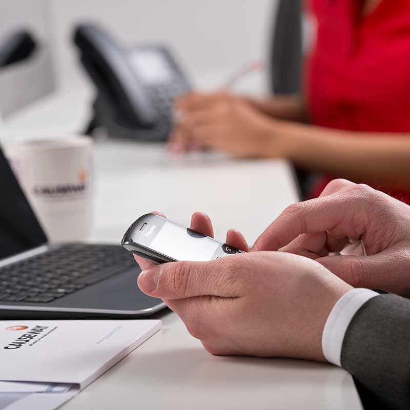 Hands holding a mobile in an office