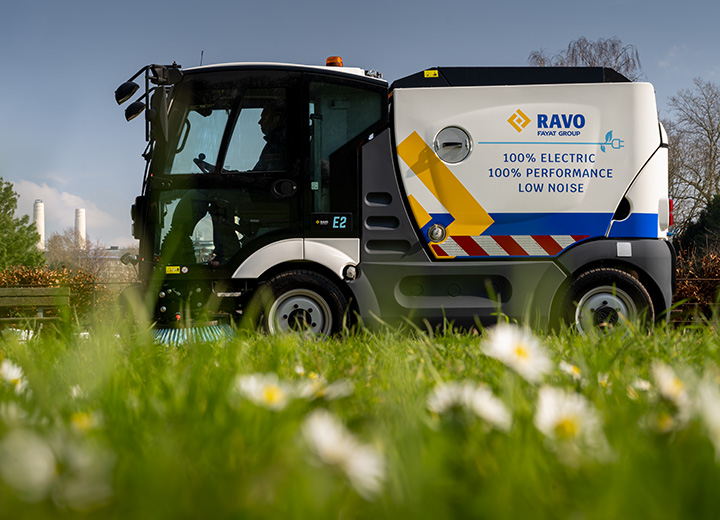 Electric Sweeper with flowers and grass in the foreground.