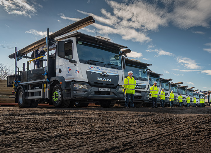 A Groiup of lorries arranged in a line with their drivers standing next to the cabs