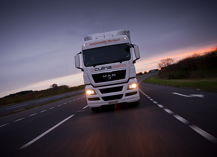 A logistics companies lorry heading towards the camera at sunset on an a road in Norfolk.