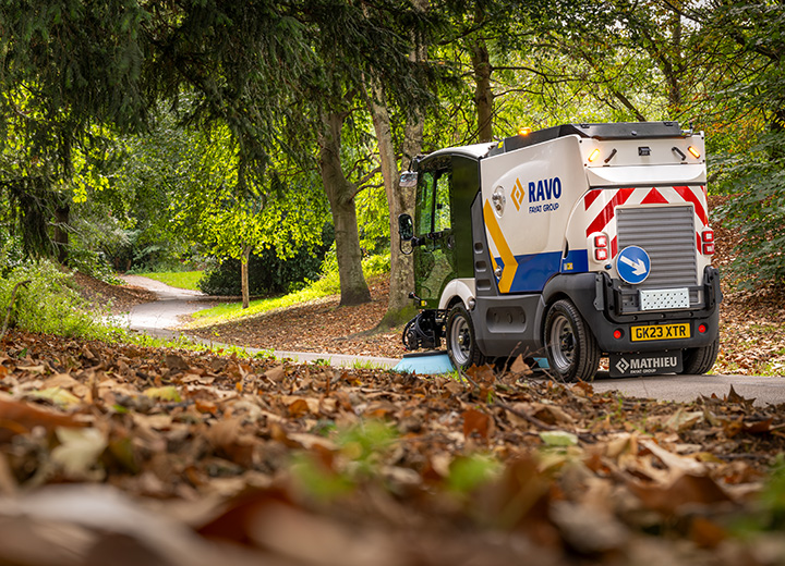 Road Sweeper working in a London park sweeping leaves from a path.