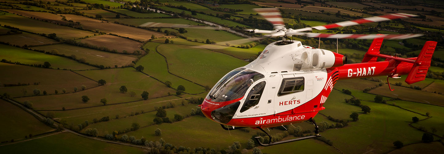 The Herts air ambulance photographed in flight over the Essex countryside from another helicopter