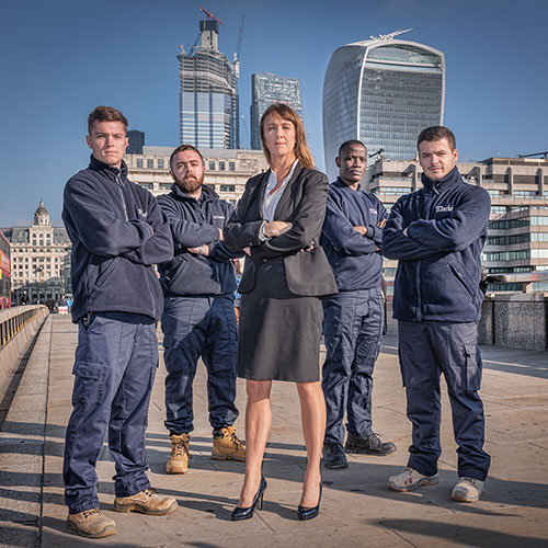 Group of apprentices and their mentor on London Bridge with the city in the background