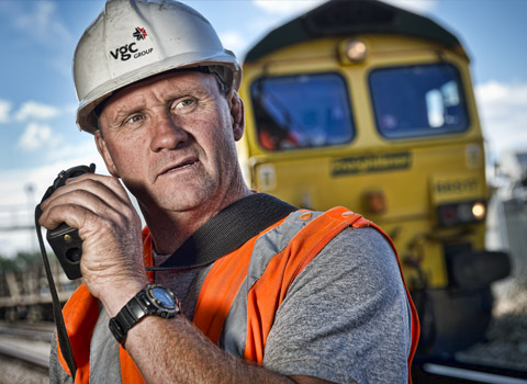Photograph of a rail worker with locomotive in background