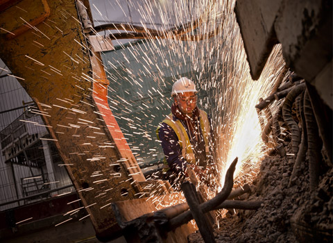 Demolition worker cutting steel bars in reinforced concrete