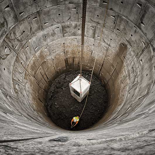 Worker in a deep excavation photographed with a very wide angle lens
