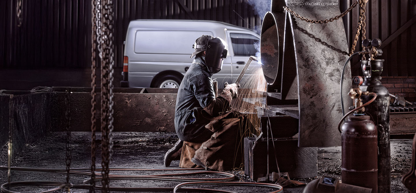 Welder working in an industrial location producing sparks and steam