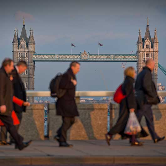 Commuters walking over London Bridge with Tower Bridge in the background