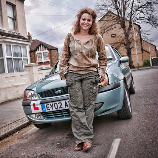 Portrait of an actress leaning against a car with an L plate