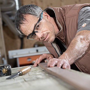 Carpenter looking along a piece of wood checking if straight